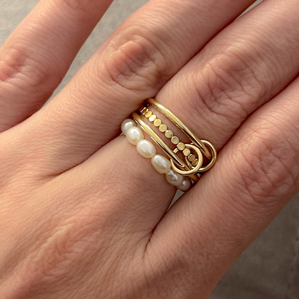 14K gold filled triple stacking ring with two smooth bands and one beaded band connected by a jump ring on hand