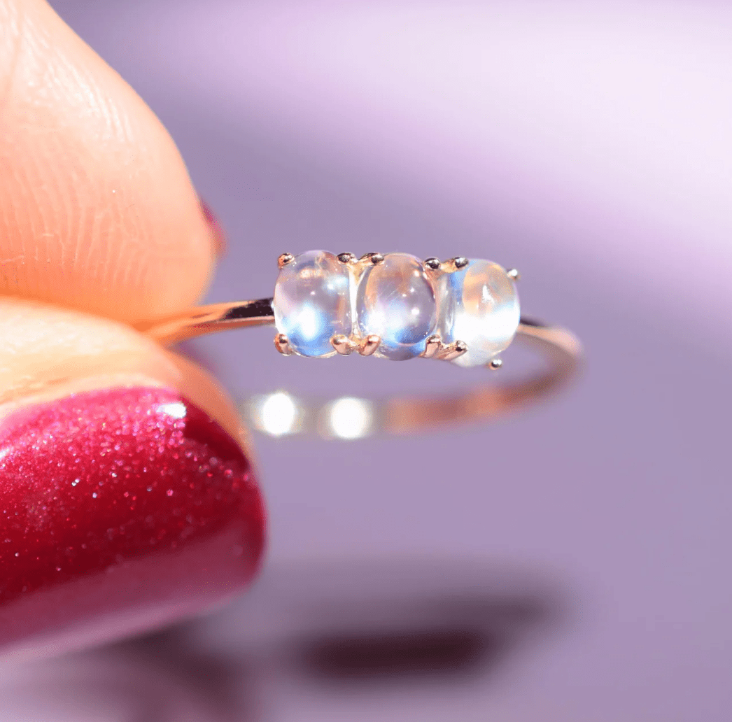 Close-up of rainbow moonstones in a 14k gold trio ring showing iridescent colors
